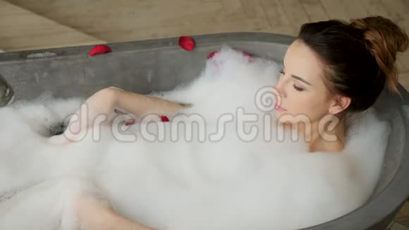 女孩躺在泡沫的大石头浴室里视频的预览图