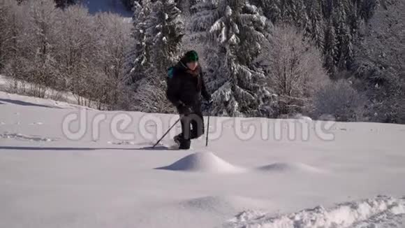 一个孤独的游客走过山林中的雪冬天雪林里的旅行者一个年轻人视频的预览图