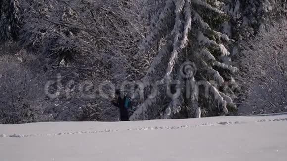 一个孤独的游客走过山林中的雪冬天雪林里的旅行者一个年轻人视频的预览图