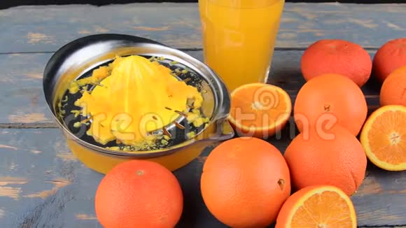 橘子橘子一杯橙汁和手动柑橘吱吱在蓝色的木制背景橘子切成两半视频的预览图