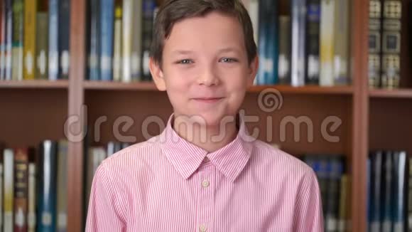 图书馆书架旁边站着一个可爱的小学生的画像视频的预览图