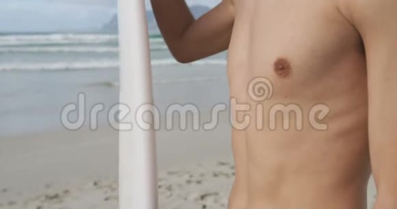 带着冲浪板在海滩上的年轻人视频的预览图