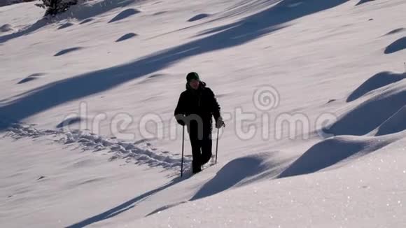 一个孤独的游客走过山林中的雪冬天雪林里的旅行者一个年轻人视频的预览图