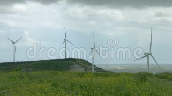 风力涡轮机螺旋桨在风中旋转风车在美丽的绿色田野上旋转视频的预览图