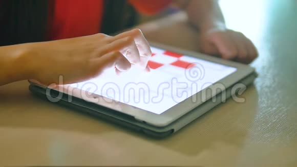 小女孩在玩数字平板电脑小女孩的生活方式坐在桌旁玩电脑游戏视频的预览图