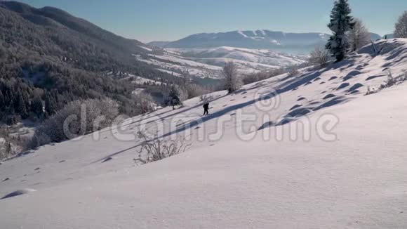 一个孤独的游客走过山林中的雪冬天雪林里的旅行者一个年轻人视频的预览图