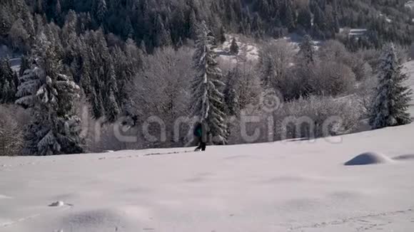 一个孤独的游客走过山林中的雪冬天雪林里的旅行者一个年轻人视频的预览图