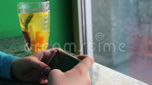 青少年在咖啡屋玩智能手机游戏旁边是柠檬茶和肉桂视频的预览图