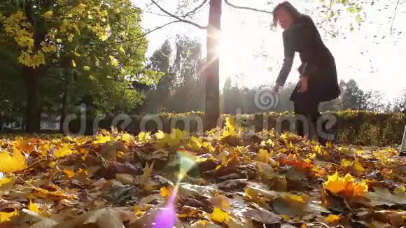一个女孩从树枝上扔出黄色的叶子视频的预览图