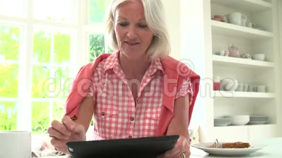 中老年妇女在早餐时看数字平板视频的预览图
