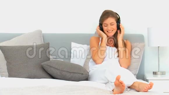 可爱的女人在床上听音乐视频的预览图