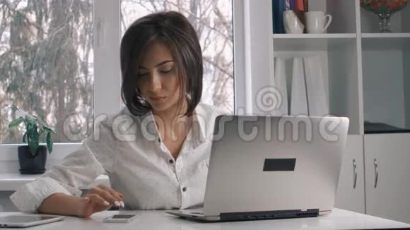 漂亮的商务女性穿着白色衬衫在办公室的笔记本电脑上工作视频的预览图
