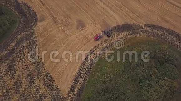空中在耕地上向无人机射击一辆红色拖拉机在秋天开垦田地视频的预览图
