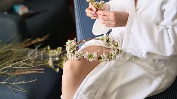 穿着白色酒店礼服的新娘编织着花环视频的预览图