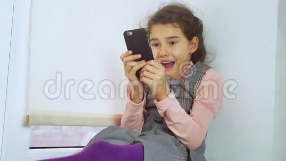 坐在窗台上上网玩智能手机的少女视频的预览图
