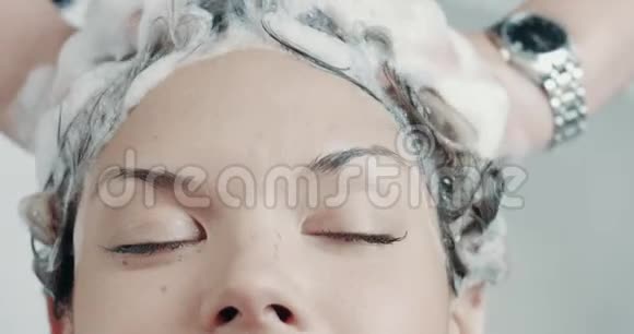 在沙龙里的白种人女人用专业的化妆师做头发处理视频的预览图