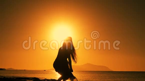 日出时在海滩上跳跃的女孩剪影视频的预览图