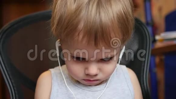 孩子在家里用耳机听智能手机上的音乐视频的预览图