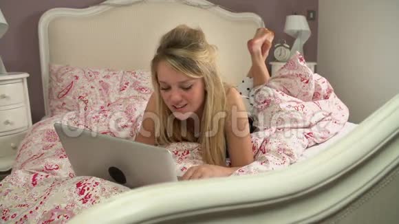 使用笔记本电脑和手机躺在床上的少女视频的预览图
