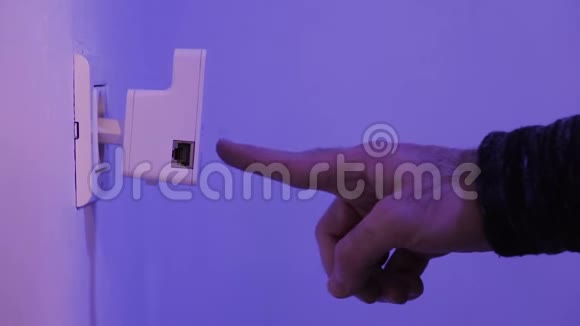 男子用手指按在WiFi连接器上的WPS按钮上这是在墙上的电气插座上视频的预览图