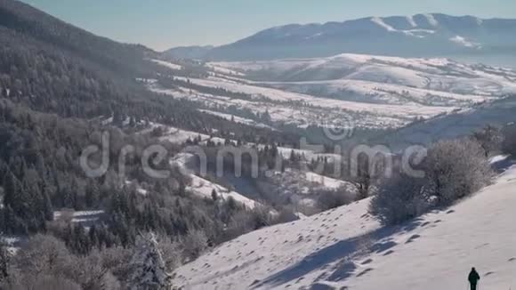 一个孤独的游客走过山林中的雪冬天雪林里的旅行者一个年轻人视频的预览图