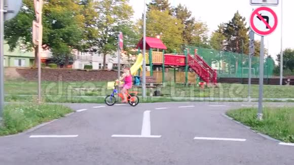 女孩在操场上骑自行车交通夏天骑自行车的小女孩视频的预览图