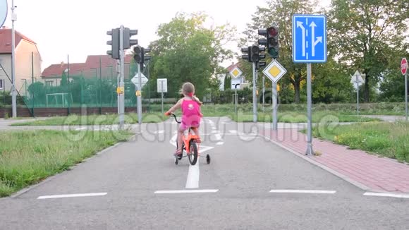 女孩在操场上骑自行车交通夏天骑自行车的小女孩视频的预览图