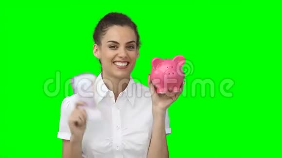 一个手里拿着钱和储蓄罐的女人视频的预览图