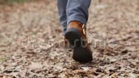 穿牛仔裤和靴子的女人在树林里散步视频的预览图