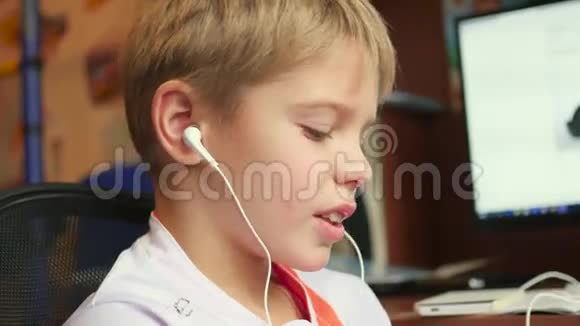 孩子在家里用耳机听智能手机上的音乐视频的预览图