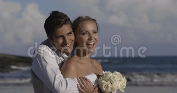 微笑着新婚夫妇拥抱在海滩上视频的预览图