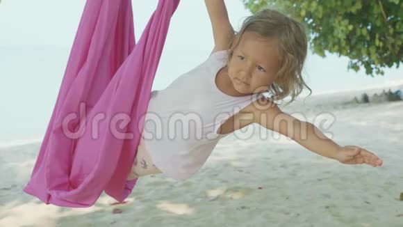 小可爱的孩子在海滩上用吊床做瑜伽视频的预览图