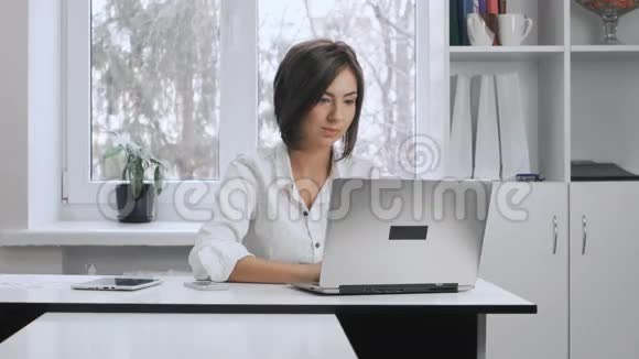 漂亮的商务女性穿着白色衬衫在办公室的笔记本电脑上工作视频的预览图