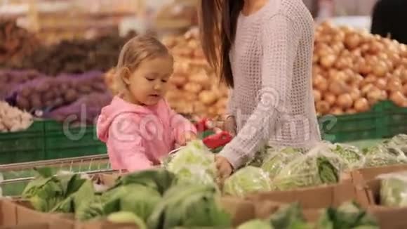 母亲和女儿在超市购物时选择蔬菜视频的预览图