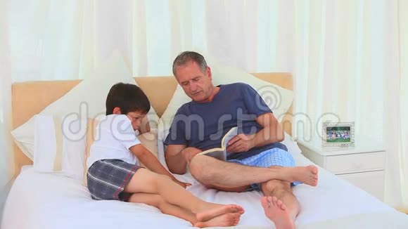 一个男人和他的孙子在看书视频的预览图