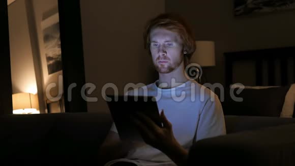 红发男子夜间使用平板电脑视频的预览图