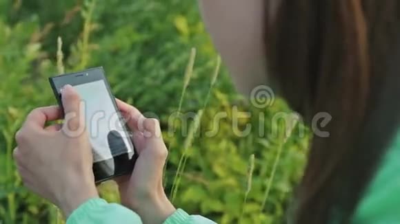 在美丽的大自然中用智能手机关闭女性双手视频的预览图