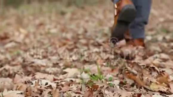 穿牛仔裤和靴子的女人在树林里散步视频的预览图