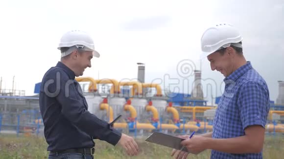 团队合作工业煤气生产站的概念慢动作录像两名戴头盔的工程师在天然气上握手视频的预览图