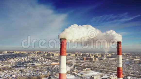 在蓝天下的冬季城市全景背景下的发电厂管道视频的预览图