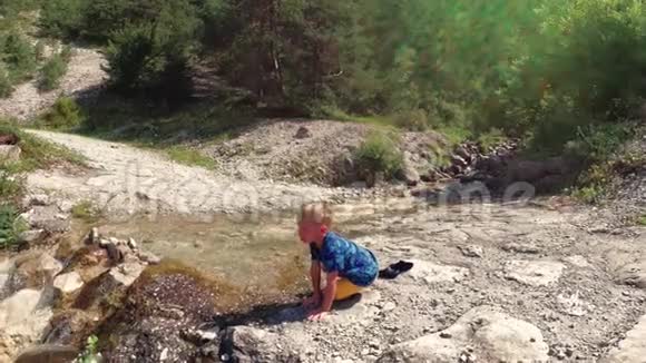 这孩子坐在溪边的石头上视频的预览图