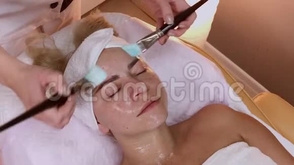 专业美容师在女人脸上涂上刷子的面膜视频的预览图