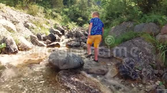 这孩子坐在溪边的石头上视频的预览图