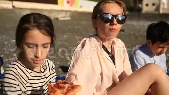 孩子们和妈妈在海滩上吃披萨视频的预览图