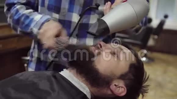 理发师正在理发店里给一个留胡子的人吹吹风视频的预览图