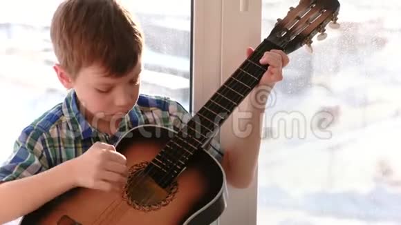 演奏乐器男孩坐在窗台上弹吉他视频的预览图