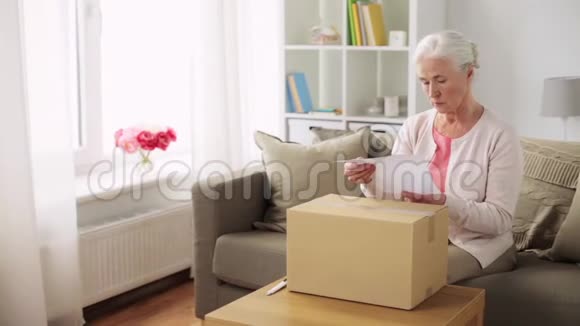 快乐的老妇人在家打开包裹盒视频的预览图
