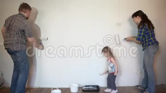 妈妈爸爸女儿的家庭用画笔和滚筒粉刷墙壁视频的预览图