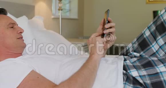 男子在床上放松时使用手机视频的预览图