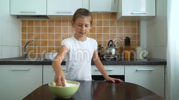 小女孩在厨房的黑桌子上准备面团揉搓面粉的工作表面视频的预览图